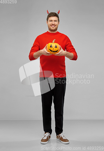 Image of happy man in halloween costume of devil over grey