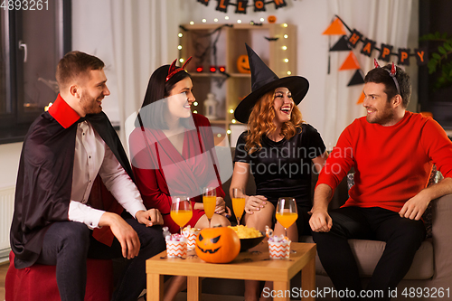 Image of happy friends in halloween costumes at home party