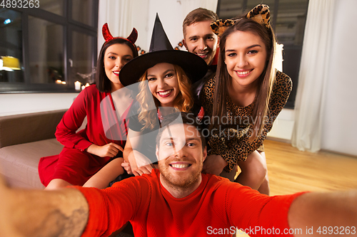 Image of happy friends in halloween costumes taking selfie