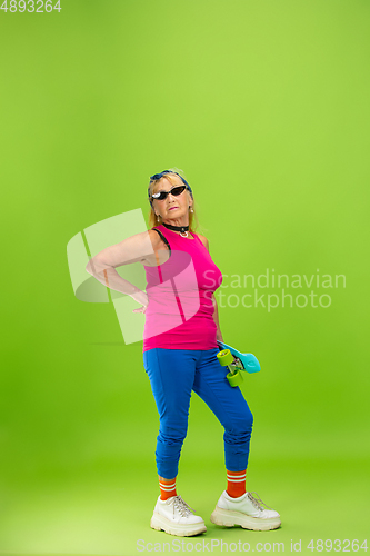 Image of Senior woman in ultra trendy attire isolated on bright green background