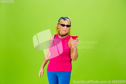 Image of Senior woman in ultra trendy attire isolated on bright green background