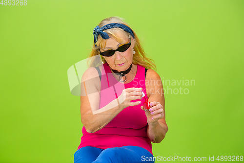 Image of Senior woman in ultra trendy attire isolated on bright green background