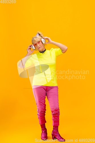 Image of Senior woman in ultra trendy attire isolated on bright orange background