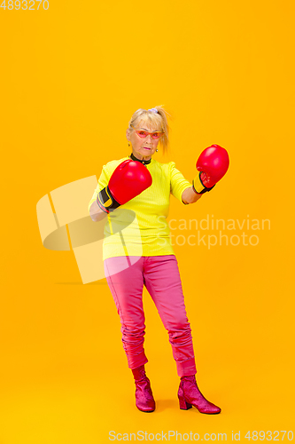 Image of Senior woman in ultra trendy attire isolated on bright orange background