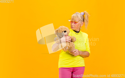 Image of Senior woman in ultra trendy attire isolated on bright orange background