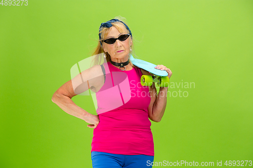 Image of Senior woman in ultra trendy attire isolated on bright green background