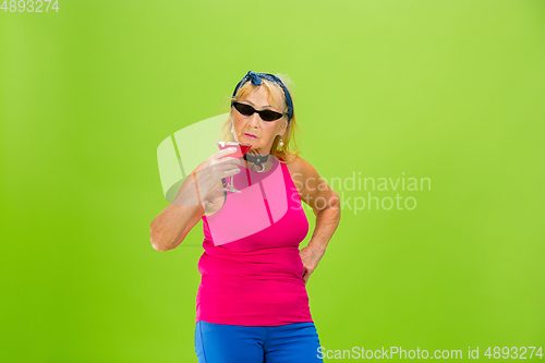 Image of Senior woman in ultra trendy attire isolated on bright green background