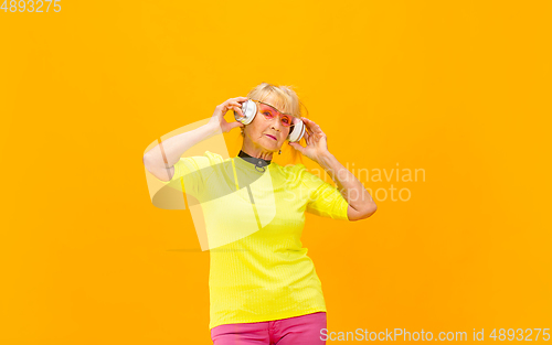 Image of Senior woman in ultra trendy attire isolated on bright orange background