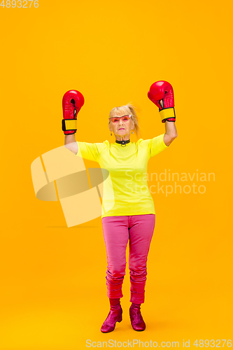 Image of Senior woman in ultra trendy attire isolated on bright orange background