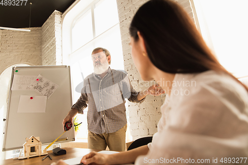 Image of Male architect-engineer presents project of future house for young family.