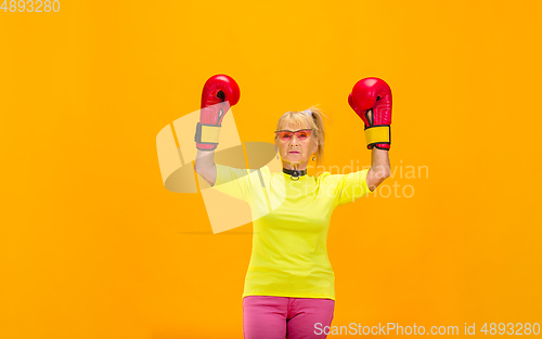 Image of Senior woman in ultra trendy attire isolated on bright orange background