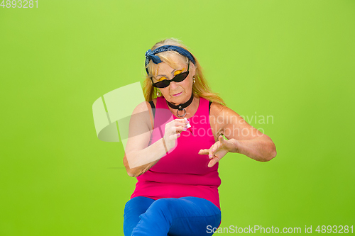 Image of Senior woman in ultra trendy attire isolated on bright green background