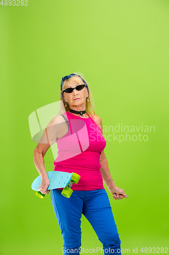 Image of Senior woman in ultra trendy attire isolated on bright green background