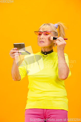 Image of Senior woman in ultra trendy attire isolated on bright orange background