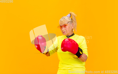 Image of Senior woman in ultra trendy attire isolated on bright orange background