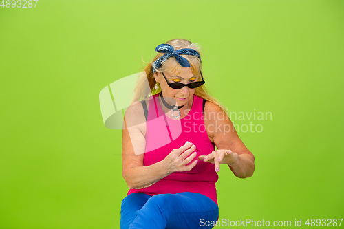 Image of Senior woman in ultra trendy attire isolated on bright green background