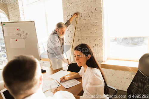 Image of Male architect-engineer presents project of future house for young family.