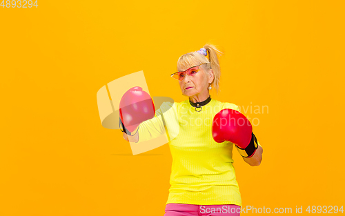 Image of Senior woman in ultra trendy attire isolated on bright orange background