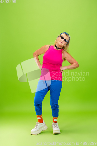 Image of Senior woman in ultra trendy attire isolated on bright green background