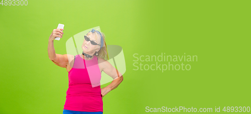 Image of Senior woman in ultra trendy attire isolated on bright green background