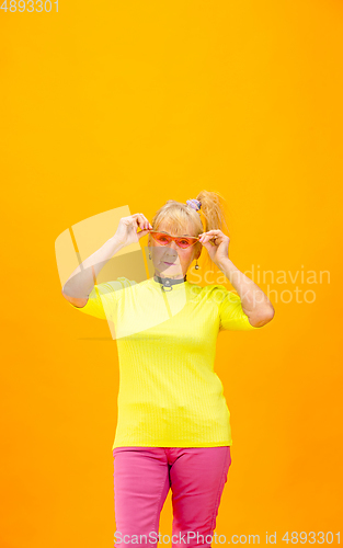 Image of Senior woman in ultra trendy attire isolated on bright orange background