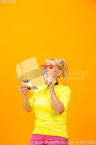 Image of Senior woman in ultra trendy attire isolated on bright orange background