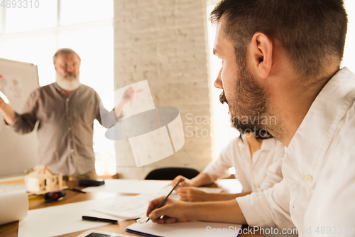 Image of Male architect-engineer presents project of future house for young family.