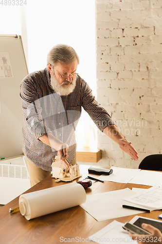 Image of Male architect-engineer presents project of future house for young family.