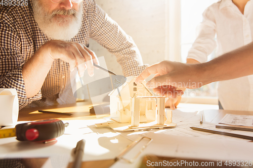 Image of Male architect-engineer presents project of future house for young family.