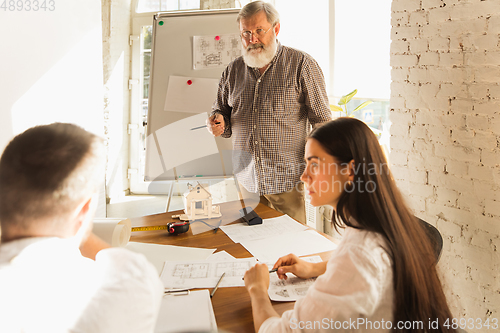 Image of Male architect-engineer presents project of future house for young family.