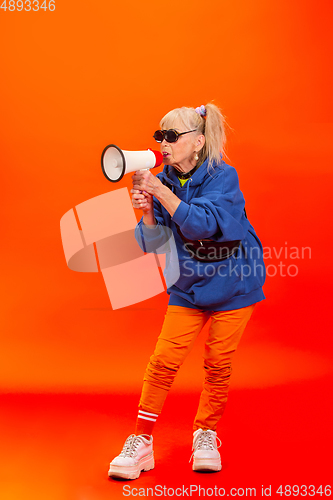 Image of Senior woman in ultra trendy attire isolated on bright orange background