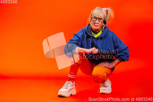 Image of Senior woman in ultra trendy attire isolated on bright orange background