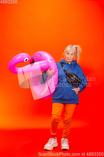 Image of Senior woman in ultra trendy attire isolated on bright orange background