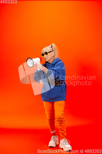 Image of Senior woman in ultra trendy attire isolated on bright orange background