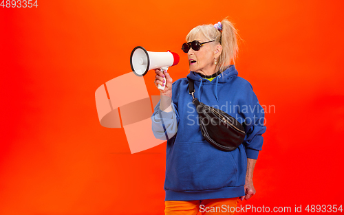 Image of Senior woman in ultra trendy attire isolated on bright orange background