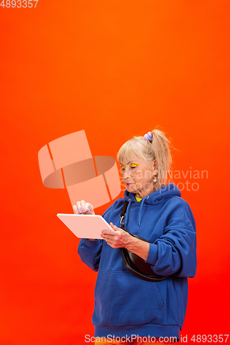 Image of Senior woman in ultra trendy attire isolated on bright orange background