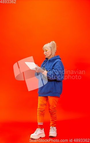 Image of Senior woman in ultra trendy attire isolated on bright orange background