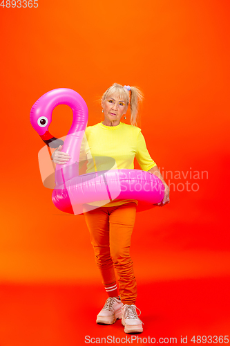 Image of Senior woman in ultra trendy attire isolated on bright orange background