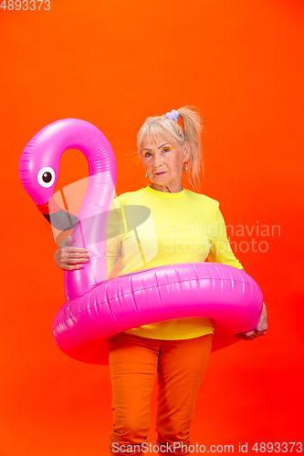 Image of Senior woman in ultra trendy attire isolated on bright orange background