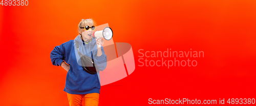 Image of Senior woman in ultra trendy attire isolated on bright orange background