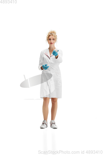 Image of Portrait of female doctor, nurse or cosmetologist in white uniform and blue gloves over white background