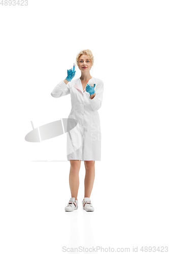 Image of Portrait of female doctor, nurse or cosmetologist in white uniform and blue gloves over white background