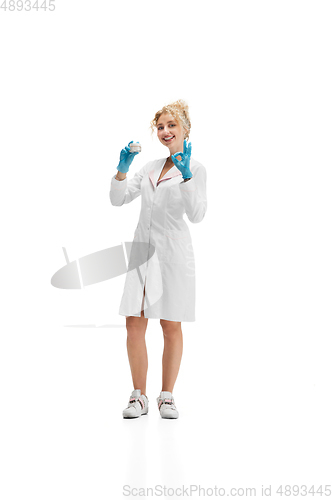 Image of Portrait of female doctor, nurse or cosmetologist in white uniform and blue gloves over white background