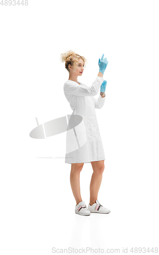 Image of Portrait of female doctor, nurse or cosmetologist in white uniform and blue gloves over white background