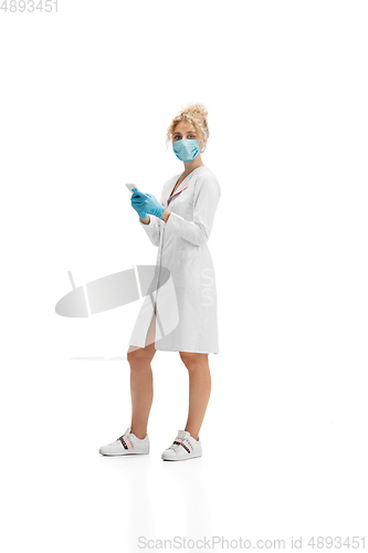 Image of Portrait of female doctor, nurse or cosmetologist in white uniform and blue gloves over white background