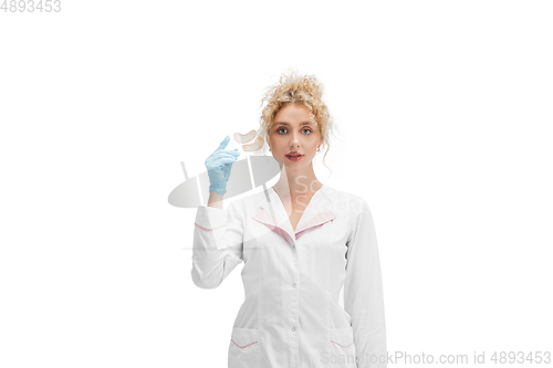 Image of Portrait of female doctor, nurse or cosmetologist in white uniform and blue gloves over white background