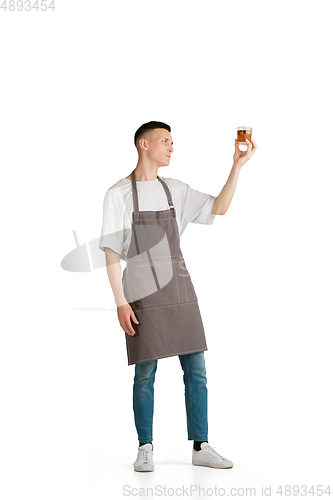 Image of Isolated portrait of a young male caucasian barista or bartender in brown apron smiling