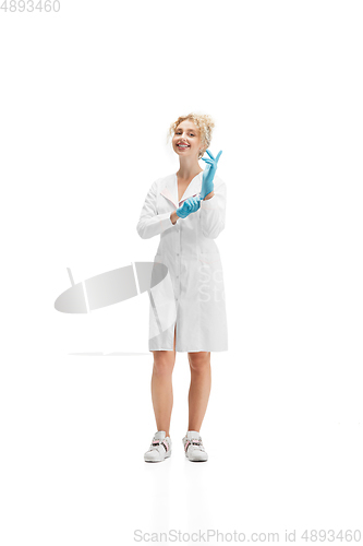 Image of Portrait of female doctor, nurse or cosmetologist in white uniform and blue gloves over white background