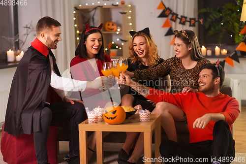 Image of happy friends in halloween costumes at home party