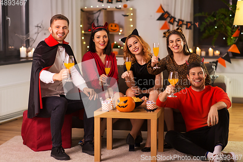 Image of happy friends in halloween costumes at home party